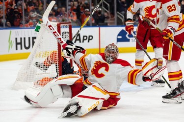 Calgary Flames' goaltender Jacob Markstrom (25) reacts after being hit by a falling Connor McDavid (97) as the Edmonton Oilers' forward scores during third period preseason NHL action at Rogers Place in Edmonton, on Monday, Oct. 4, 2021.