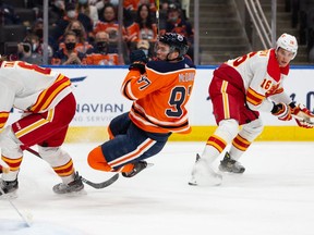 Edmonton Oilers' Connor McDavid (97) collides with Calgary Flames' goaltender Jacob Markstrom (25) during third period preseason NHL action at Rogers Place in Edmonton, on Monday, Oct. 4, 2021. McDavid was credited with a goal after deflecting a shot from Jesse Puljujarvi (13).