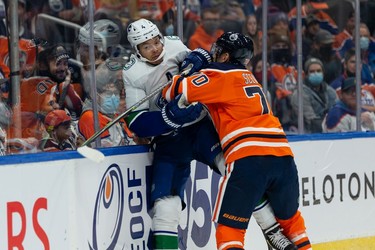 Edmonton Oilers' Colton Sceviour (70) hits Vancouver Canucks' Madison Bowey (4) during the first period of preseason NHL action at Rogers Place in Edmonton, on Thursday, Oct. 7, 2021.