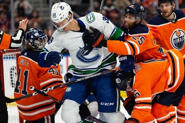 Edmonton Oilers' Darnell Nurse (25) wrestles with Vancouver Canucks' Alex Chiasson (39) during the second period of preseason NHL action at Rogers Place in Edmonton, on Thursday, Oct. 7, 2021.