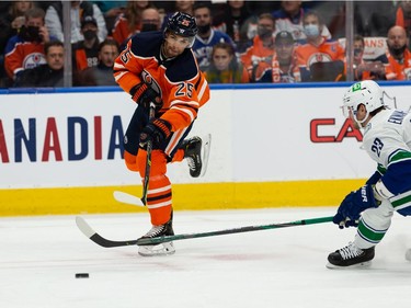 Edmonton Oilers' Darnell Nurse (25) shoots past Vancouver Canucks' Oliver Ekman-Larsson (23) during first period NHL action at Rogers Place in Edmonton, on Wednesday, Oct. 13, 2021.