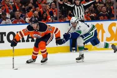 Edmonton Oilers' Connor McDavid (97) battles Vancouver Canucks' Quinn Hughes (43) during first period NHL action at Rogers Place in Edmonton, on Wednesday, Oct. 13, 2021.