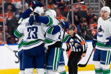 Vancouver Canucks' Oliver Ekman-Larsson (23) celebrates a goal with teammates on Edmonton Oilers' goaltender Mike Smith (41) during third period NHL action at Rogers Place in Edmonton, on Wednesday, Oct. 13, 2021.