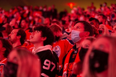 Hockey fans sing the national anthem as the Edmonton Oilers play the Vancouver Canucks during NHL action at Rogers Place in Edmonton, on Wednesday, Oct. 13, 2021.