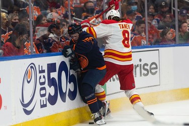 Edmonton Oilers' Kailer Yamamoto (56) battles Calgary Flames Christopher Tanev (8) during first period NHL action at Rogers Place in Edmonton, on Saturday, Oct. 16, 2021.