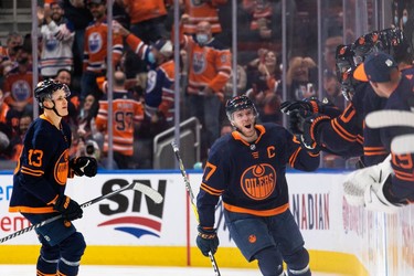 Edmonton Oilers' Connor McDavid (97) celebrates a goal on Calgary Flames goaltender Jacob Markstrom (25) with teammates during second period NHL action at Rogers Place in Edmonton, on Saturday, Oct. 16, 2021.