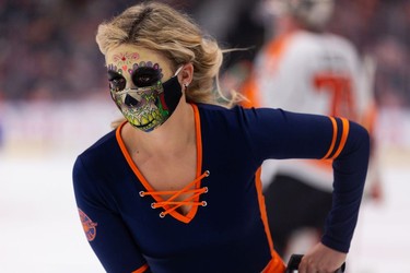 A member of the Edmonton Oilers rink team wears a Halloween mask as the team plays the Philadelphia Flyers during first period NHL action at Rogers Place in Edmonton, on Wednesday, Oct. 27, 2021.