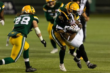 Edmonton Elks' Trumaine Washington (8) and Jordan Hoover (28) tackle Hamilton Tiger-Cats' Don Jackson (5) during first half CFL action at Commonwealth Stadium in Edmonton, on Friday, Oct. 29, 2021.