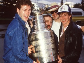 Edmonton Oilers Kevin Lowe, left, equipment manager Lyle 'Sparky' Kulchisky, Mark Messier and Wayne Gretzky hold the Stanley Cup after leaving David's Restaurant in Edmonton on May 21, 1984.