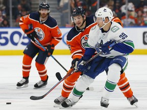 Oct 7, 2021; Edmonton, Alberta, CAN; Vancouver Canucks forward Alex Chiasson (39) and Edmonton Oilers forward Zach Hyman (18) chase a loose puck during the third period at Rogers Place.