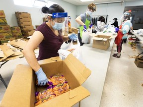 Amy Wong packs fresh produce for a non-profit called Grocery Run that provides food hampers for free to any family that connects with them through another agency called the Multicultural Health Brokers Cooperative, on Friday, June 18, 2021 in Edmonton. Prior to the pandemic the organization was delivering 100 hampers to families a week. They now provide more than 550 hampers to families in need of fresh produce. Greg Southam-Postmedia