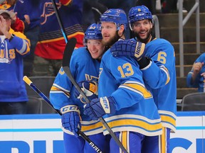 Jake Neighbours (left) of the St. Louis Blues celebrates his first career NHL goal with teammates Kyle Clifford (13) and Marco Scandella (6) in the second period against the Los Angeles Kings at Enterprise Center on October 23, 2021 in St Louis, Missouri.