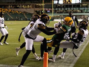 Edmonton Elks slotback Greg Ellingson (82) wrestles with Hamilton Tiger-Cats’ Ciante Evans (0) at Commonwealth Stadium in Edmonton on Friday, Oct. 29, 2021.