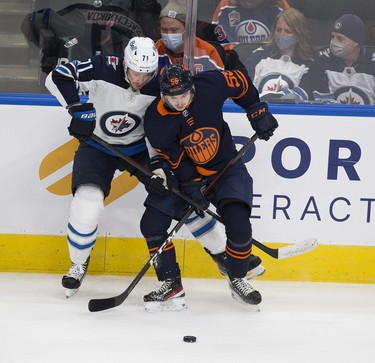 Edmonton Oilers Kailer Yamamoto (56) and Winnipeg Jets Evgeny Svechnikov (71) battle for the puck during first period NHL action on Thursday, Nov. 18, 2021 in Edmonton.
