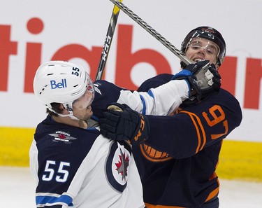 Edmonton Oilers Connor McDavid (97) and Winnipeg Jets  Mark Scheifele (55) rough it up during second period NHL action on Thursday, Nov. 18, 2021 in Edmonton.