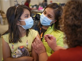 Sofia Flores Rojas, 9, sits with her mom Alejandra as she recieves a COVID-19 vaccine in Calgary, Alta., on November 26, 2021. Leah Hennel / AHS