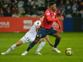 Lille's Canadian forward Jonathan David (R) fights for the ball with Angers' French midfielder Vincent Manceau (L) during the French L1 football match between Lille OSC and Angers SCO at Stade Pierre-Mauroy in Lille, northern France on November 6, 2021.