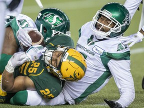 Edmonton Elks running back Walter Fletcher (25) holds onto the ball after being tackled by Saskatchewan Roughriders Loucheiz Purifoy (5), right, and and Deon Lacey (45) in Edmonton on Friday, Nov. 5, 2021.