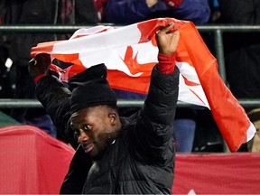 Alphonso Davies, d'Équipe Canada, quitte le terrain avec le drapeau canadien au-dessus de sa tête après que son équipe a battu l'équipe du Costa Rica 1-0 lors d'un match de football de qualification pour la Coupe du monde de la FIFA 2022 qui s'est tenu au stade du Commonwealth à Edmonton, au Canada, le vendredi 12 novembre 2021.