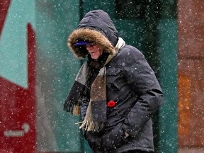 A pedestrian walks on Jasper Avenue in downtown Edmonton on Sunday November 14, 2021 as snow flurries descended upon city. (PHOTO BY LARRY WONG/POSTMEDIA)