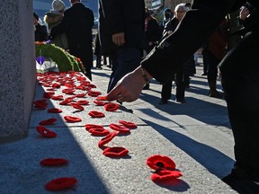 Attendees of the Remembrance Day ceremony place red poppies on the cenotaph outside Edmonton City Hall on Nov. 11, 2021. Photo by Ed Kaiser, Postmedia.