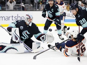 Chris Driedger #60 of the Seattle Kraken makes a save in front of Tyler Benson #16 of the Edmonton Oilers during the first period at Climate Pledge Arena on December 18, 2021 in Seattle, Washington.