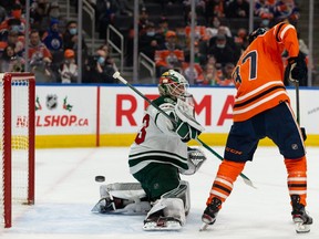 Edmonton Oilers forward Warren Foegele (37) and Minnesota Wild’s goaltender Cam Talbot (33) reach for a flying puck during first period NHL action at Rogers Place in Edmonton, on Tuesday, Dec. 7, 2021.