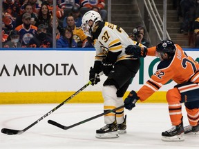 Edmonton Oilers’ Darnell Nurse (25) battles Boston Bruins’ Patrice Bergeron (37) during second period NHL action at Rogers Place in Edmonton, on Thursday, Dec. 9, 2021.