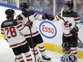 Team Canada's Ryan O’Rourke (28), Elliot Desnoyers (19) and Connor Bedard (16) celebrate a first-period goal against Team Austria during the IIHF world junior championship in Edmonton on Tuesday, Dec. 28, 2021.