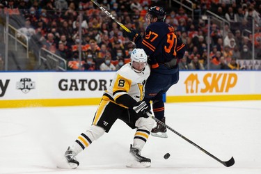 Edmonton Oilers' Connor McDavid (97) is checked by Pittsburgh Penguins' Brian Dumoulin (8) during first period NHL action at Rogers Place in Edmonton, on Wednesday, Dec. 1, 2021.