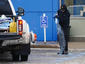 Kalin Kidd applies de-icer at a southwest Edmonton parking lot on Wednesday December 8, 2021. Freezing rain was creating havoc in the Edmonton region.