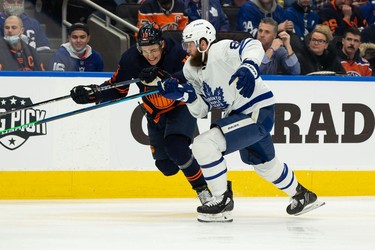 Edmonton Oilers' Jesse Puljujarvi (13) battles Toronto Maple Leafs' Jake Muzzin (8) during first period NHL action at Rogers Place in Edmonton, on Tuesday, Dec. 14, 2021.