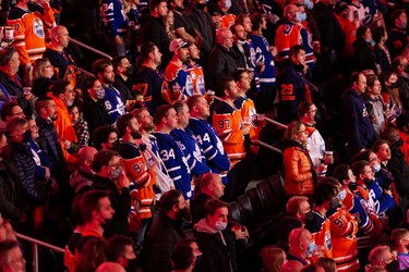 Hockey fans sing the national anthem as the Edmonton Oilers play the Toronto Maple Leafs during a NHL game at Rogers Place in Edmonton, on Tuesday, Dec. 14, 2021.