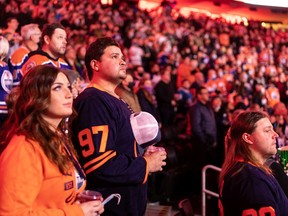 Hockey fans sing the national anthem as the Edmonton Oilers take on the Columbus Blue Jackets during a NHL game at Rogers Place in Edmonton on Dec. 16, 2021.