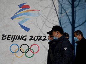 In this file photo taken on Dec.1, 2021, people walk past the Beijing 2022 Winter Olympics logo at the Shougang Park in Beijing.