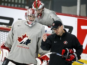 Goalie Dylan Garand, left, and goalie Sebastian Cossa, centre, listen to goaltending coach Olivier Michaud during a practice at the Canadian World Junior Hockey Championships selection camp in Calgary, Thursday, Dec. 9, 2021.