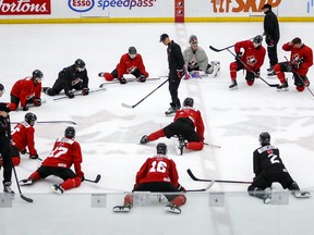 Players stretch as head coach Dave Cameron, centre, gives instruction during a practice at the Canadian world junior championships selection camp in Calgary on Dec. 9, 2021.