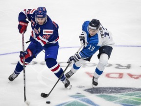 L'Américain Red Savage (20 ans) et le Finlandais Juuso Maenpaa (19 ans) s'affrontent pour la rondelle lors de leur match hors-concours pour le championnat du monde junior de l'IIHF à Edmonton le jeudi 23 décembre 2021.