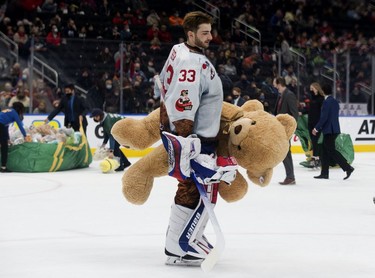 Oil Kings goaltender Sebastian Cossa (33) carries a teddy bears off the ice following a first period goal during the Oil Kings' 14th annual Teddy Bear Toss, in Edmonton Saturday Dec. 4, 2021.