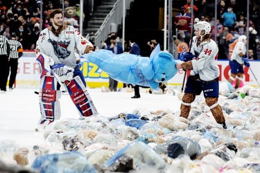 Goaltender Sebastian Cossa (33) and Carter Souch (44) tear open a plastic bag surrounding a teddy bears, following a first period goal during the Oil Kings' 14th annual Teddy Bear Toss, in Edmonton Saturday Dec. 4, 2021.