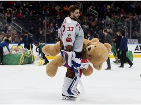 Oil Kings goaltender Sebastian Cossa carries a teddy bear off the ice following a first period goal during the Oil Kings' 14th annual Teddy Bear Toss in Edmonton on Saturday, Dec. 4, 2021.