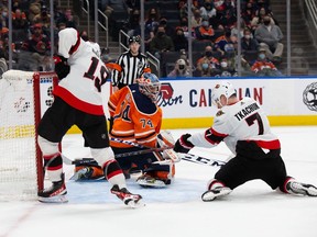 Goaltender Stuart Skinner #74 of the Edmonton Oilers concedes a goal under pressure from Drake Batherson #19 and Brady Tkachuk #7 of the Ottawa Senators during the third period at Rogers Place on January 15, 2022.