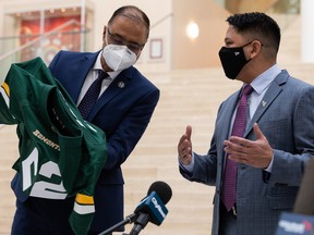 Edmonton Mayor Amarjeet Sohi (left) receives an Edmonton Elks jersey from new club president and CEO Victor Cui at City Hall on Tuesday, Jan. 25, 2022.