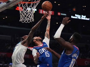 Minnesota Timberwolves forward Jarred Vanderbilt (8) and L.A. Clippers guard Xavier Moon (15) and forward James Ennis (10) reach for the ball at Crypto.com Arena in Los Angeles on Jan. 3, 2022.