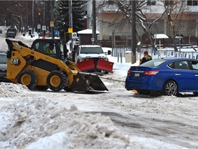A bobcat helps to free a stuck vehicle along the residential road of 88 Ave. which is being plowed as windrows create a challenge for drivers until they're done in Edmonton, January 12, 2022.