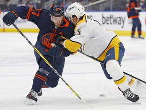 Nashville Predators defencemen Matt Benning (5) knocks the puck away from Edmonton Oilers forward Connor McDavid (97) at Rogers Place on Thursday, Jan. 27, 2022.