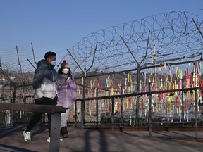 Visitors walk past a military fence decorated with ribbons wishing for peace and reunification of the Korean Peninsula at the Imjingak peace park near the Demilitarized zone (DMZ) dividing the two Koreas in Paju on January 1, 2022.