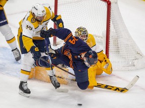 Edmonton Oilers' Devin Shore (14) is tripped up by Nashville Predators goalie Juuse Saros (74) and Roman Josi (59) on Thursday, Jan. 27, 2022 in Edmonton.