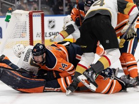 The Edmonton Oilers’ Devin Shore (14) lands on goaltender Mike Smith (41) as they play the Vegas Golden Knights at Rogers Place in Edmonton on Feb. 8, 2022.