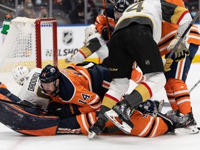 Edmonton Oilers' Devin Shore (14) lands on goaltender Mike Smith (41) as they play the Las Vegas Golden Knights at Rogers Place in Edmonton on Feb. 8, 2022.